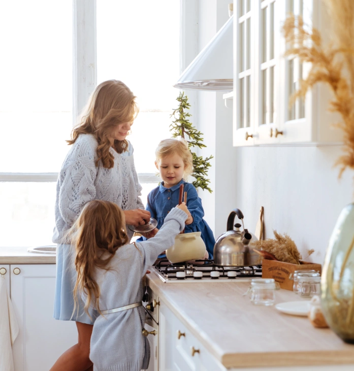 Mother and two young children spending time together in a bright kitchen with white cabinetry and wooden countertops