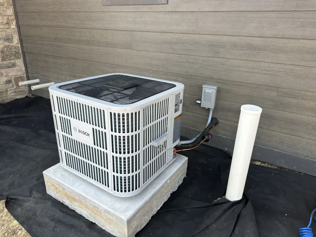 Bosch outdoor HVAC condenser unit installed on a concrete pad beside a home's exterior wall