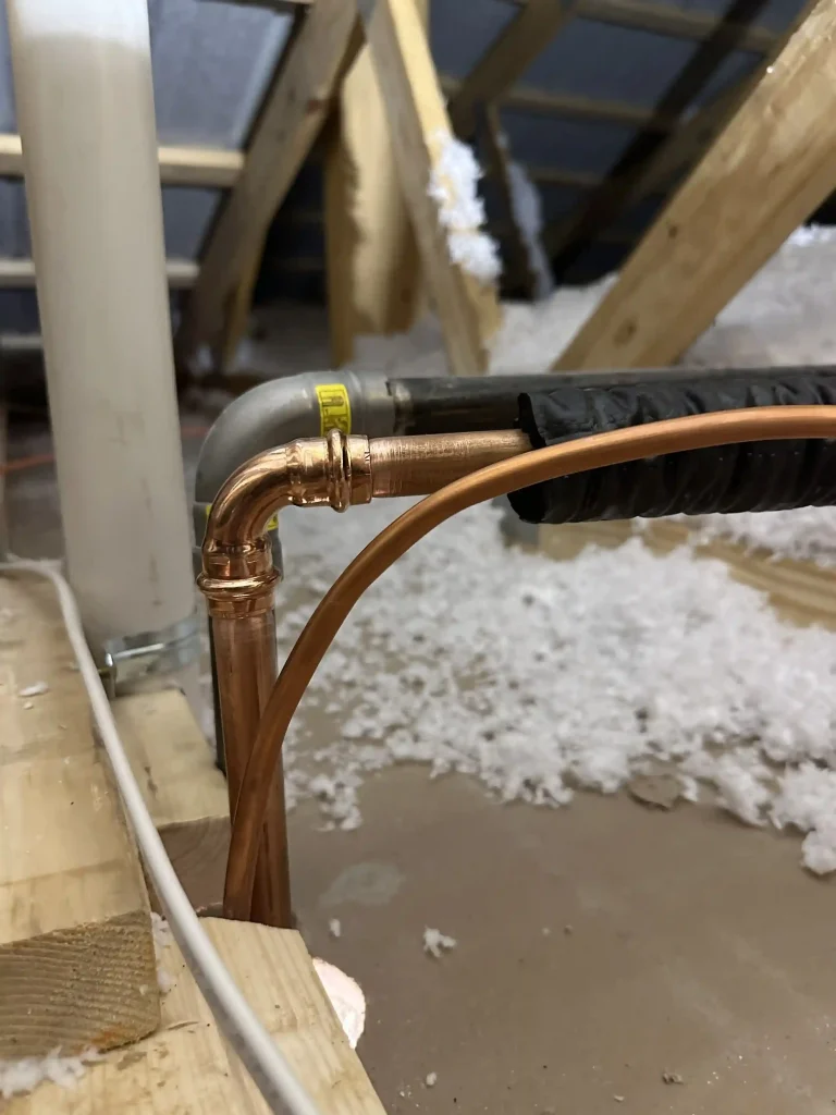 Copper refrigerant piping and insulated HVAC lines installed in an unfinished residential attic