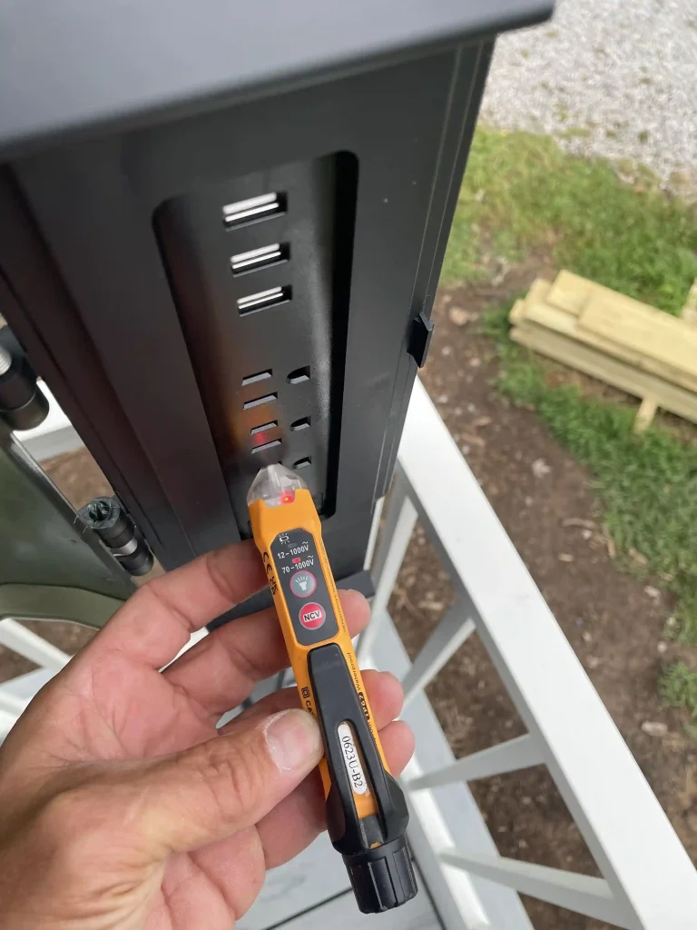 Electrician using a non-contact voltage tester to check an outdoor electrical outlet for power